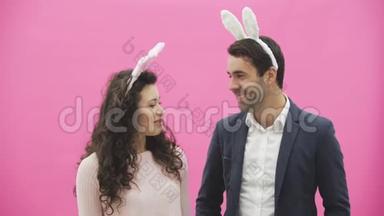 站在粉红色背景上的年轻夫妇。在这段时间里，他们的耳朵都是乌合之众。看每一个